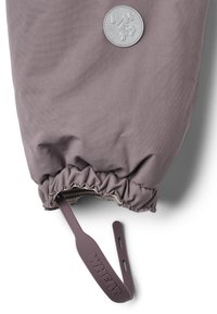 Lilla kangaga mansett elastse kogumisega ja reguleeritava rihmaga, millel on silt "WHEAT" ning ümmargune applikeeritud märk, millel on reljeefsed "WHEAT" tähed.