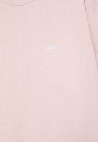 Sweat-shirt rose clair avec petit logo blanc brodé sur la partie supérieure de la poitrine et col rond.