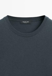 Mørkegrå bomulds-T-shirt med glat tekstur, rund halsudskæring og synlige syninger. Labelen viser "Massimo Dutti," der angiver mærkets oprindelse.
