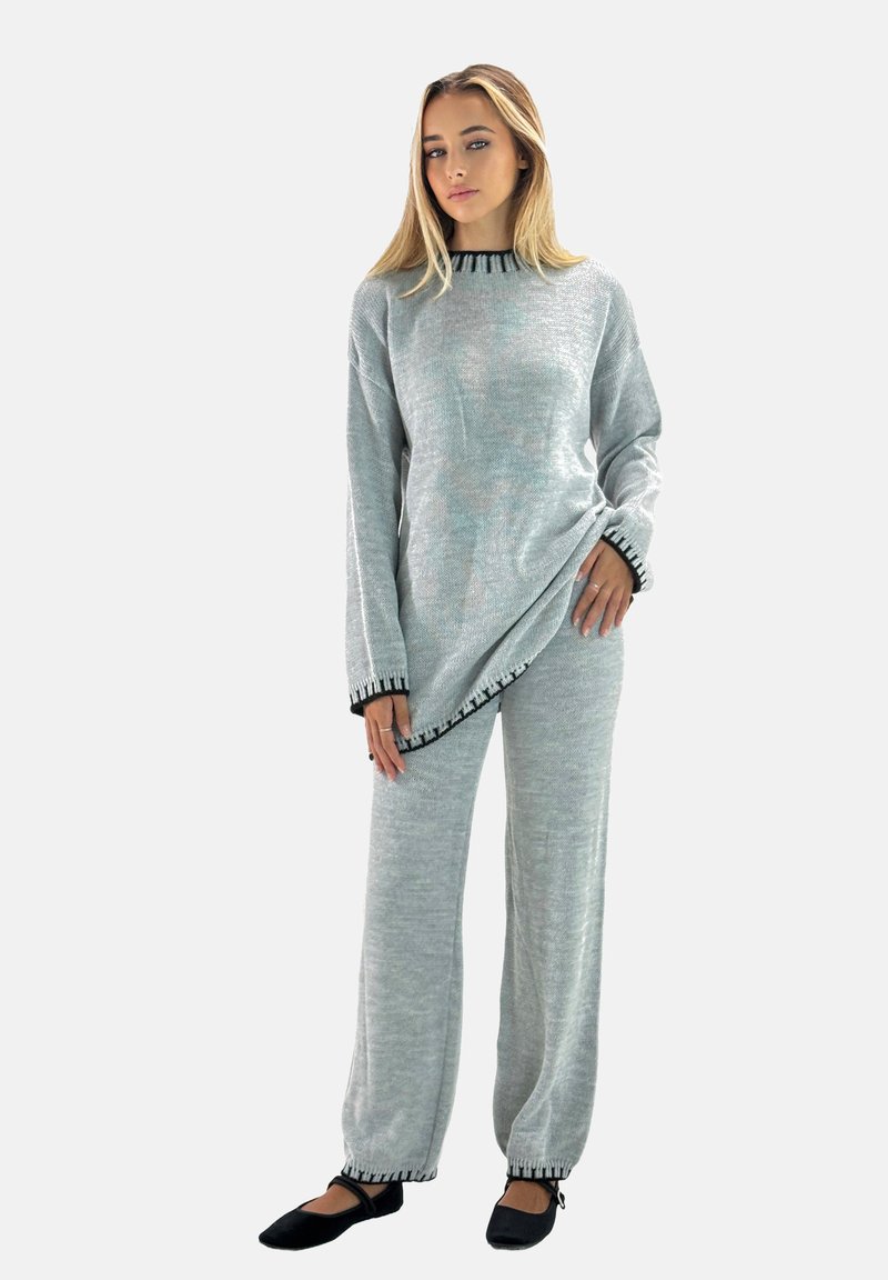 Conjunto de lounge gris de punto con un diseño asimétrico, que presenta un ribete negro en el escote y los dobladillos, y pantalones holgados y relajados.
