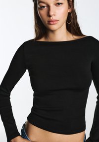 Zwarte top met lange mouwen in een aansluitend design met een geribbelde textuur en een boothals, gedragen met denim shorts met een medium taillehoogte.