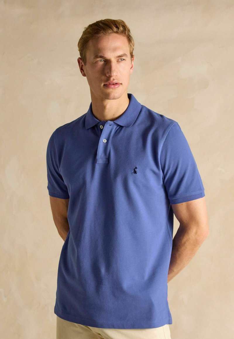 Vīriešu īssleeve polo krekls gaiši zilā kokvilnā, ar klasisku apkakli, trīs pogu slēgšanu un izšūtu logo uz krūtīm.