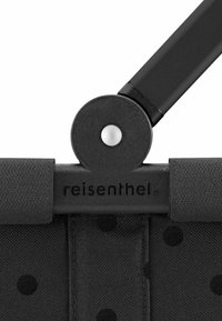 Schwarzer Stoff mit einem Punktenmuster, ausgestattet mit einem Kunststoffverbindungselement und einem Riemendetail, mit dem eingprägten Markennamen "reisenthel".