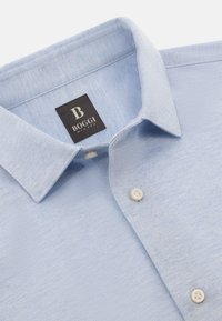 Hellblaues Hemd mit Knopfleiste aus strukturiertem Stoff. Verfügt über einen spitzen Kragen, zwei Knöpfe und ein Etikett mit "BOGGI MILANO".