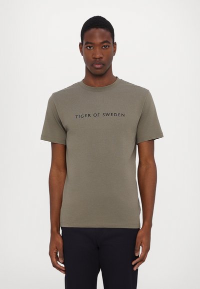 Tricou verde măsliniu dintr-un material moale, cu mâneci scurte și guler rotund. Textul negru "TIGER OF SWEDEN" centrat pe piept.