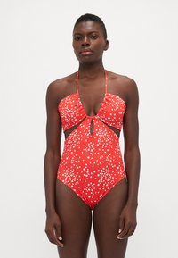 Rode bloemen zwemkleding met een uitsnijding in de taille, halternek met strik en een klein sleutelgaten detail aan de voorkant. Gladde stofstructuur.