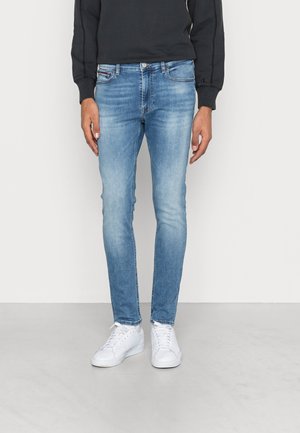 Ljusblå slim-fit jeans av denim, med en blekt tvätt och standard fem-ficka design, tillsammans med vita sneakers.
