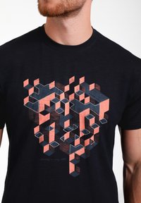 Melnas kokvilnas T-krekls ar ģeometrisku grafiku koralla un zilās tonī, ar slāņainām heksagonālām un kubiskām formām un baltiem šuvju akcentiem.