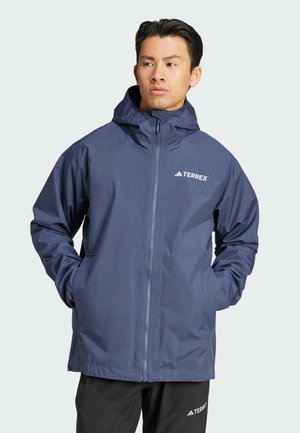 Chaqueta impermeable azul marino con un alto cuello, capucha ajustable, cremallera completa y bolsillos laterales; presenta el logo TERREX en blanco.