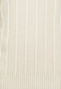 Suéter de malha em bege cremoso, com padrões texturizados, riscas verticais e um cós e punhos canelados.