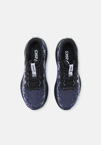 Baskets de sport noires et marine avec une tige à motifs, un mesh texturé, des lacets noirs et des accents de logo blanc sur la languette et les côtés.