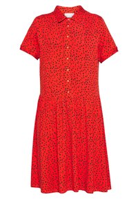 Červené šaty s krátkým rukávem a límečkem, s předním zapínáním na knoflíky a nařasenou sukní, zdobené černými puntíky po celé ploše.