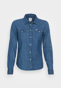 Denim long-sleeve shirt in dark blue with two chest pockets and pearl snaps, featuring a collar and a straight hem. Smooth texture.