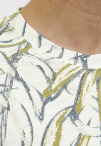 Tricou cu mânecă scurtă, guler rotund, din material ușor. Prezintă modele abstracte de frunze galbene și gri pe un fond alb.