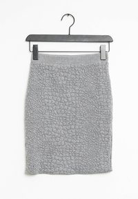 Jupe grise texturée avec un motif en forme de bulles, en matériau doux et au design ajusté. Accrochée à un crochet en métal noir.