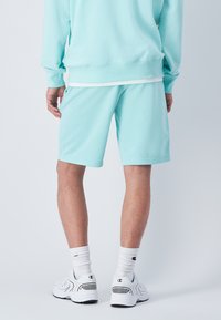 Conjunto de sudadera y pantalones cortos de algodón celeste, que presenta un ajuste relajado, mangas y pantalones cortos con puños, acentos en blanco y una textura suave.