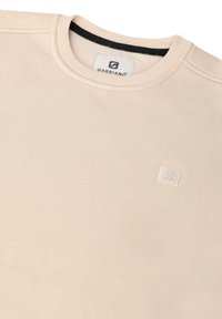 Felpa beige realizzata in tessuto di tipo testurizzato, con collo rotondo, colletto a costine e una piccola etichetta bianca con logo sul davanti.
