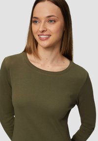 Olivengrünes Langarmshirt mit Rundhalsausschnitt, aus weichem Stoff gefertigt und taillierter Passform, mit glatter Textur und minimaler Detailgestaltung.