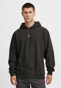 Mørkegrøn sweatshirt med hætte lavet af en bomuldsblanding, med et logo-patch foran, snoretræk i hætten og ribbede manchetter samt en afslappet pasform.
