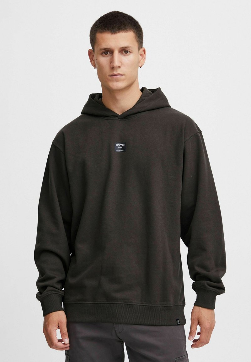 Mørkegrøn sweatshirt med hætte lavet af en bomuldsblanding, med et logo-patch foran, snoretræk i hætten og ribbede manchetter samt en afslappet pasform.