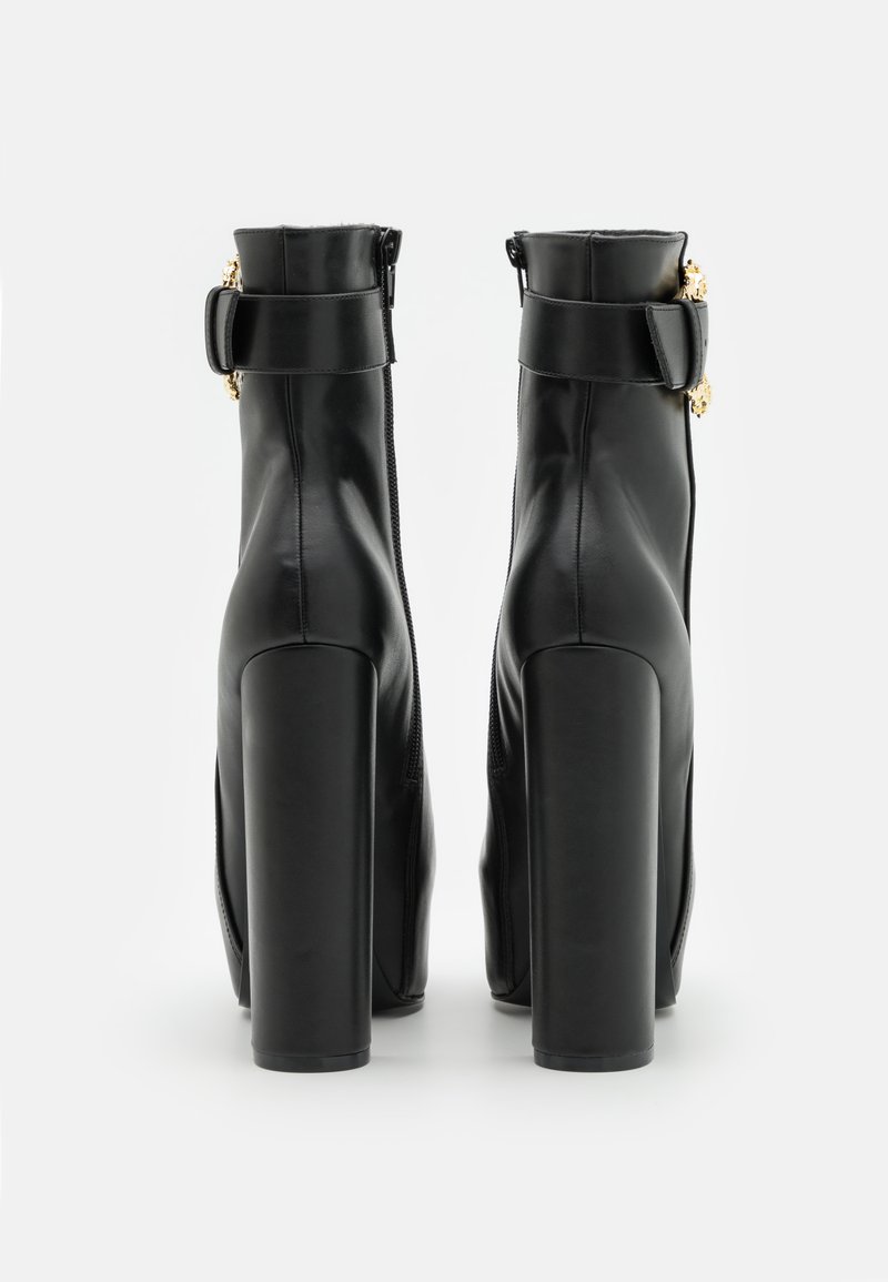 Stivaletti neri in pelle con un design elegante, caratterizzati da dettagli in metallo dorato, tacchi a blocco alti e una chiusura zip sul retro.