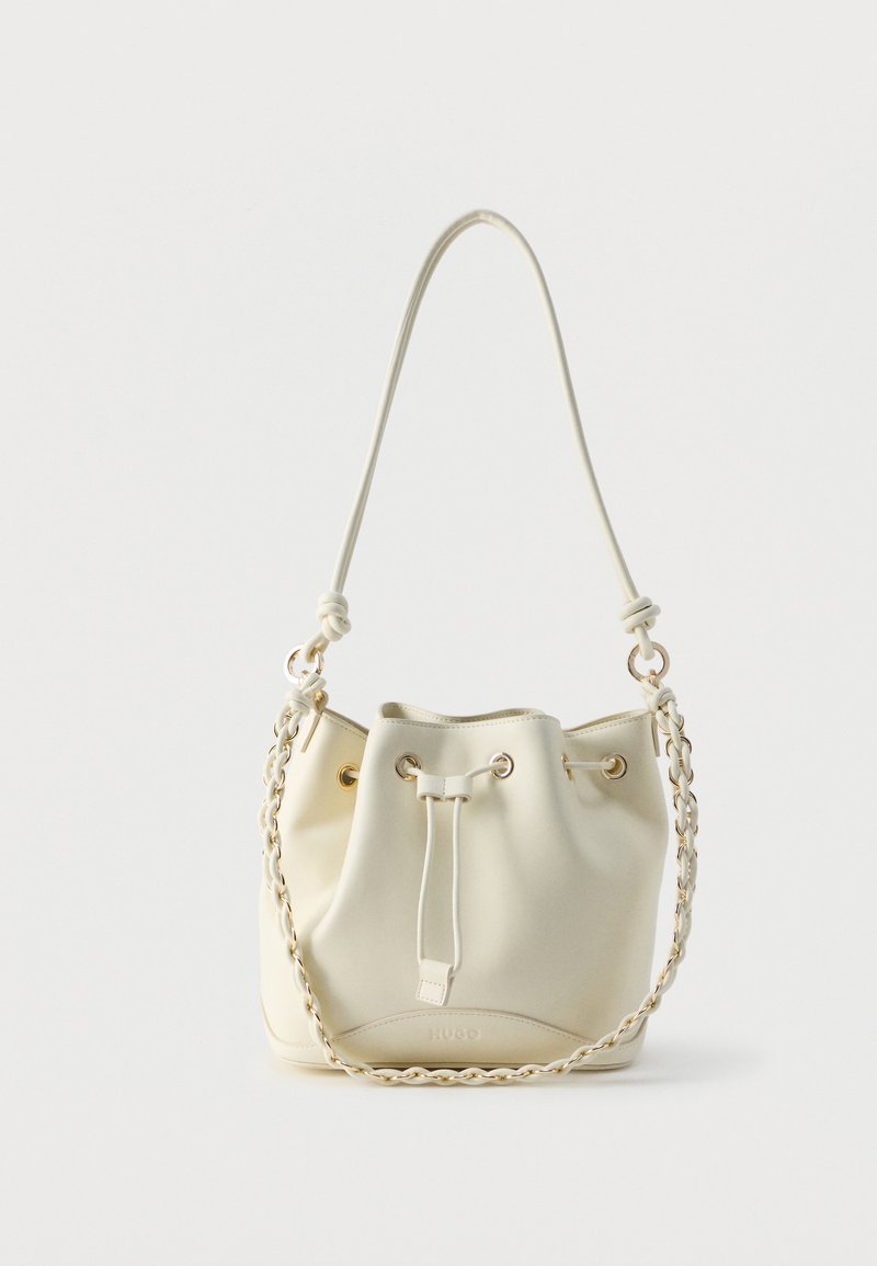 Sac seau en cuir crème avec fermeture à cordon, chaîne tressée et bandoulière en cuir, ainsi que des œillets dorés.