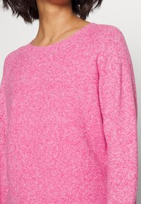 Rosa Strickpullover mit Rundhalsausschnitt, weicher Textur und langen Ärmeln, mit einem Farbverlaufseffekt.
