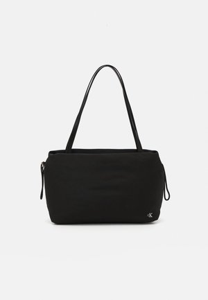 Pehmeästä kankaasta valmistettu musta olkalaukku, jossa on jämäkkä muoto, kaksinkertaiset kahvat ja pieni logokoriste sivulla.