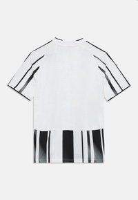 Chemise blanche à manches courtes présentant des rayures noires verticales en bas et sur les manches, avec un col rond et une texture subtile.