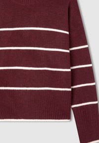 Bordowy sweter z poziomymi białymi paskami, z prążkowanym dołem i mankietami, zaprezentowany od części środkowej do rękawów na jasnym tle.