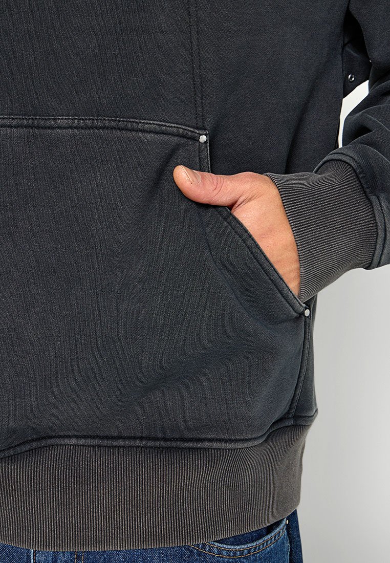 Dunkelgrauer Hoodie mit Kängurutasche, gerippten Bündchen und Saum, strukturiertem Stoff und leicht lockerer Passform. Hardware-Detail in der Nähe der Tasche sichtbar.