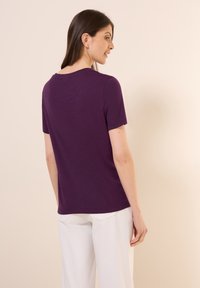 Krátký rukáv fialové tričko vyrobené z měkké tkaniny, nabízející volný střih a kulatý výstřih, s hladkým povrchem a minimalistickým designem.