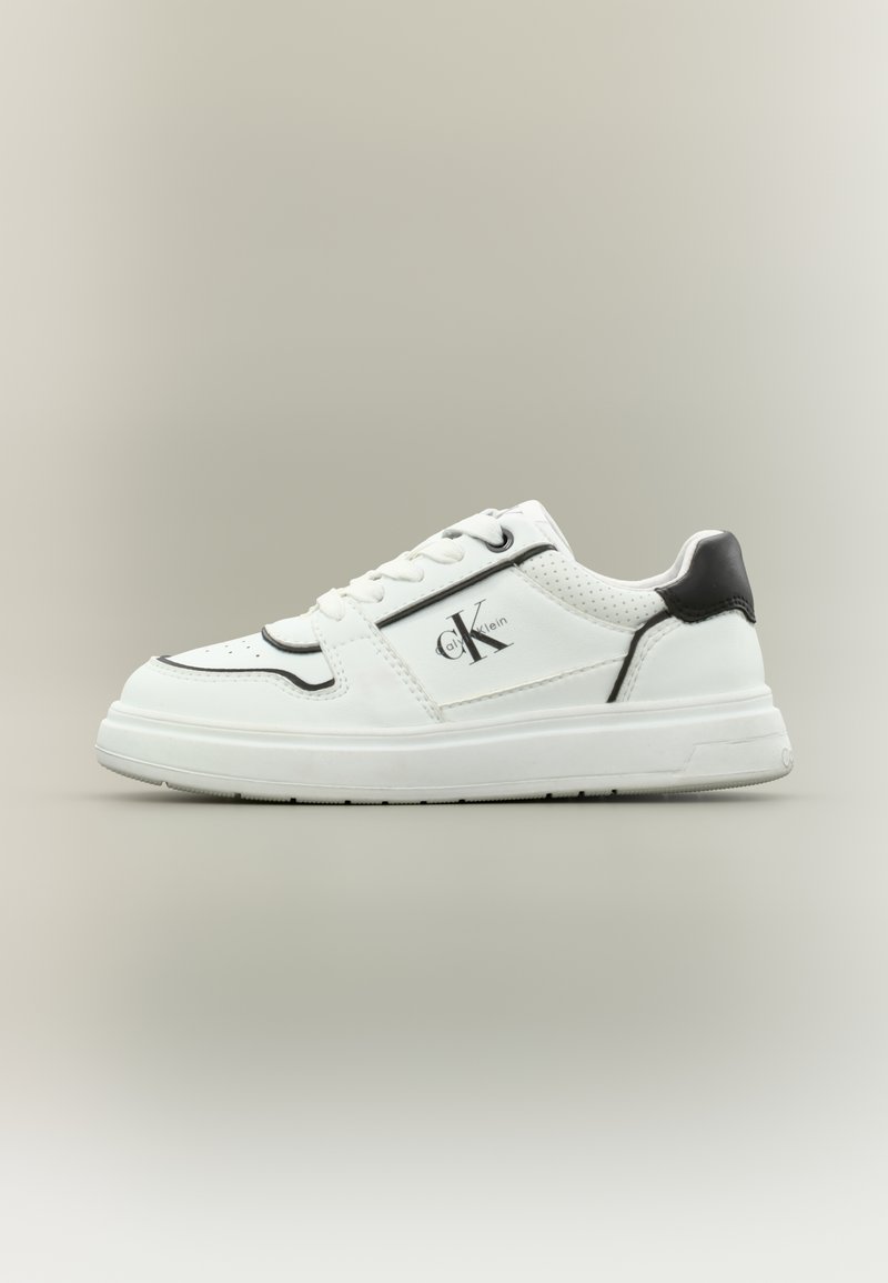 Άσπρο αθλητικό παπούτσι με μαύρες λεπτομέρειες, που διαθέτει διάτρητα τμήματα, κορδόνια στο μπροστινό μέρος και λογότυπο στο πλάι. Λείο δερμάτινο υλικό και παχιά σόλα.