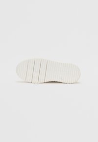 Sole di sneaker bianca con scanalature orizzontali e marchio incassato, realizzata in gomma, caratterizzata da una superficie liscia e bordi arrotondati.