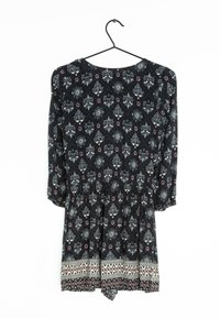 Černý overal s vzorem, třičtvrtečními rukávy a květinovými motivy, s elastickým pasem a geometrickým lemem na spodním okraji.