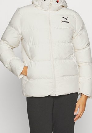 White puffer jacket with hood, zipped front, and black Puma logo on chest, worn with black pants, hand in pocket.