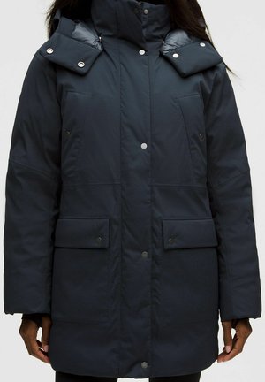 Zwarte gewatteerde winterjas met een hoge kraag, drukknoopsluiting, twee borstzakken en twee grote voorzakken met klep.