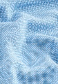 Tela tejida de color azul claro con un patrón de cuadrícula texturizado. Suave, ligera y con una apariencia ligeramente arrugada, que muestra sutiles matices en los tonos.