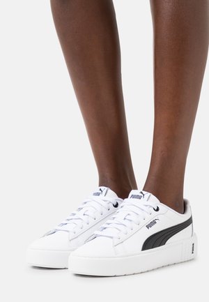 Baskets blanches avec un design texturé, dotées d'une bande Puma noire, fermeture à lacets sur le dessus et col rembourré pour le confort.