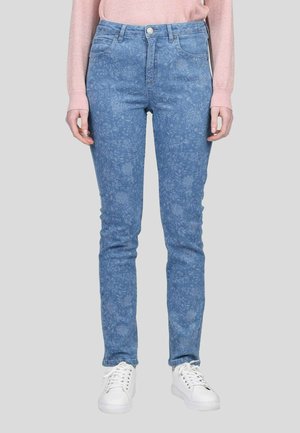 Jean en denim bleu à motif floral, coupe slim, avec un design à cinq poches et une fermeture à bouton. Associé à des baskets blanches pour le contraste.