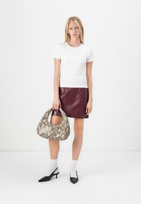 Hvit kortermet topp, burgunder ekte skinn mini skjørt, og mønstret slangeskinn veske. Modellen har på seg svarte slingback hæler og hvite sokker.