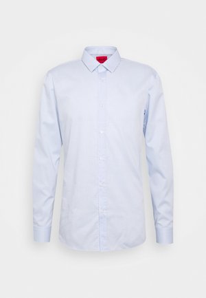Camicia da uomo azzurro chiaro a maniche lunghe con bottoni, colletto appuntito e etichetta interna rossa sul collo, su sfondo semplice.