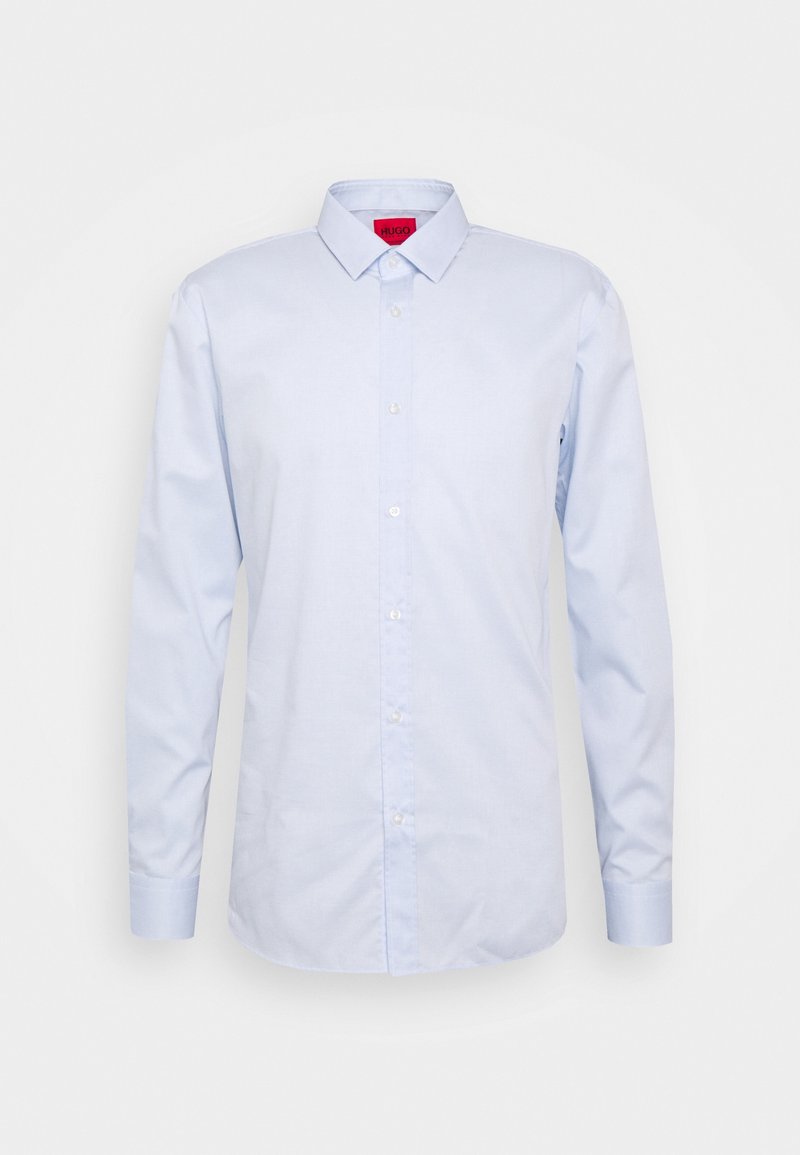 Chemise habillée bleu clair à manches longues avec col pointu et étiquette intérieure rouge sur fond uni.