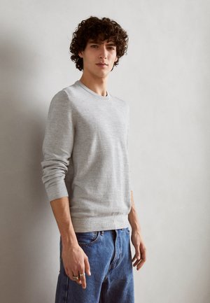 Grau gestrickter Pullover mit Rundhalsausschnitt und langen Ärmeln, kombiniert mit blauen Jeans. Die Textur wirkt glatt mit subtilen Details.