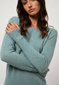 Ljus teal cashmere-sweater med ribbat halsringning och ärmslut, med en avslappnad passform och mjuk textur. Släta, minimala designelement.