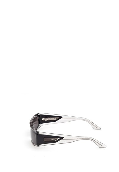 Gafas de sol rectangulares negras y transparentes con varillas anchas y transparentes y el logo "GCDS" en la patilla.
