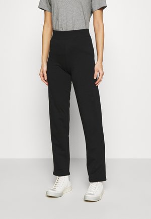 Svarta högmidjade byxor med rak benform, tillverkade av mjukt material, kombinerade med vita sneakers och en grå t-shirt.