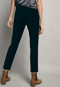 Svarta åtsittande kordbyxor med en slät textur och rak passform. Bärs med bruna ankelstövlar med sidodragkedja.