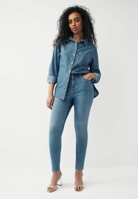 Helesinine denim-särk nööbiga, pikkade varrukatega ja tasku detailiga. Kombineeritud sobivate helesiniste kitsaste teksade ja metallik kontsadega.