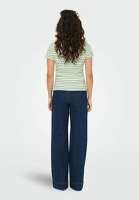 Stribet grøn og hvid tætsiddende t-shirt kombineret med højtaljede, mørkeblå vide jeans. Outfittet har en afslappet, løstsiddende pasform.